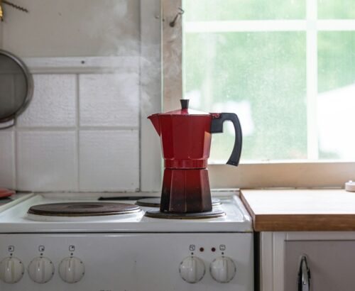 a red coffee pot sitting on top of a stove